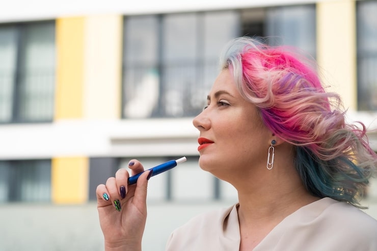 Woman with colorful hair holding a blue vape